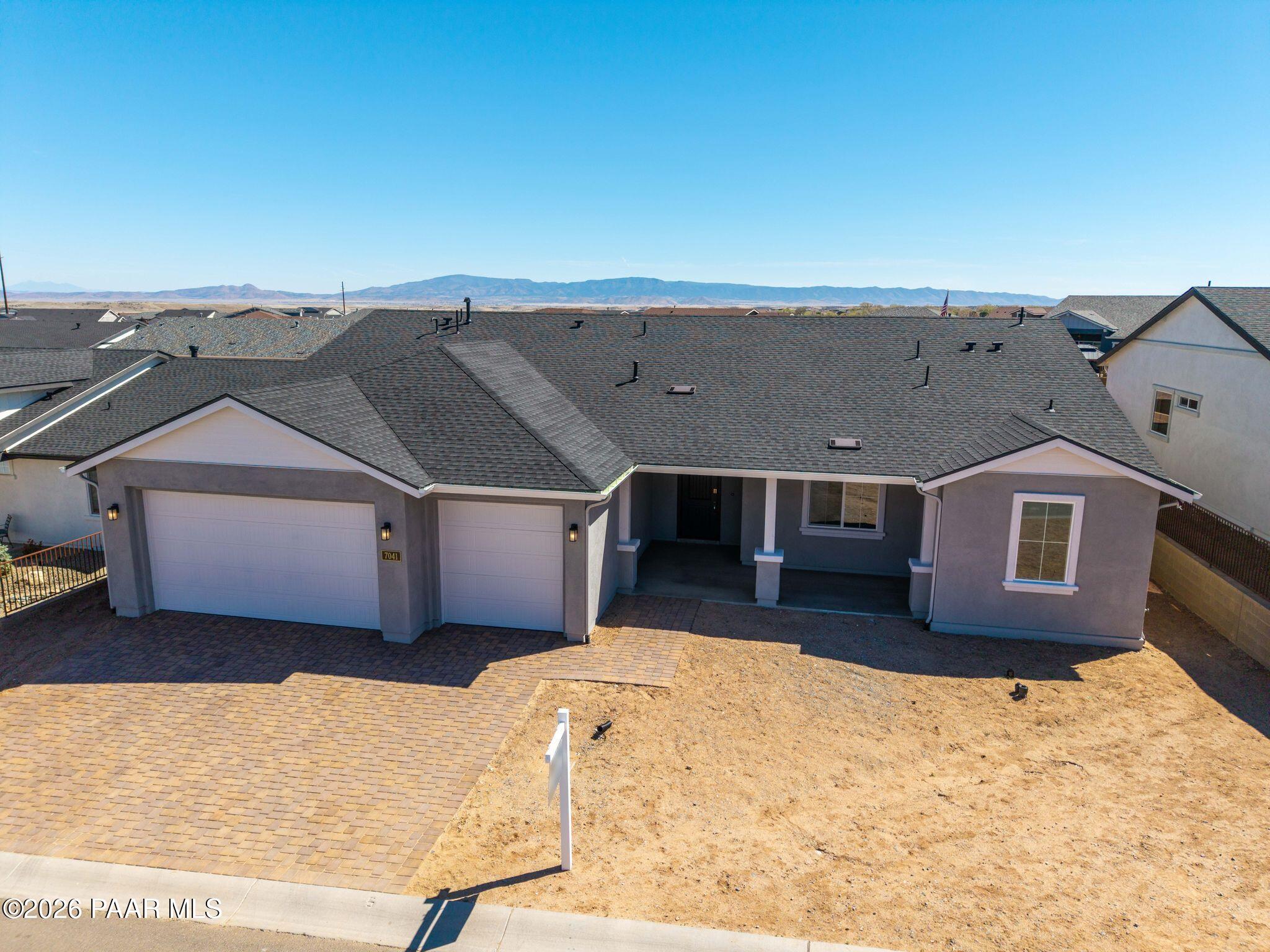 Modern single-story home with 3-car garage, gray siding, paver driveway, and mountain views in Westwood, Prescott, Arizona - Davidson Homes Monarch A