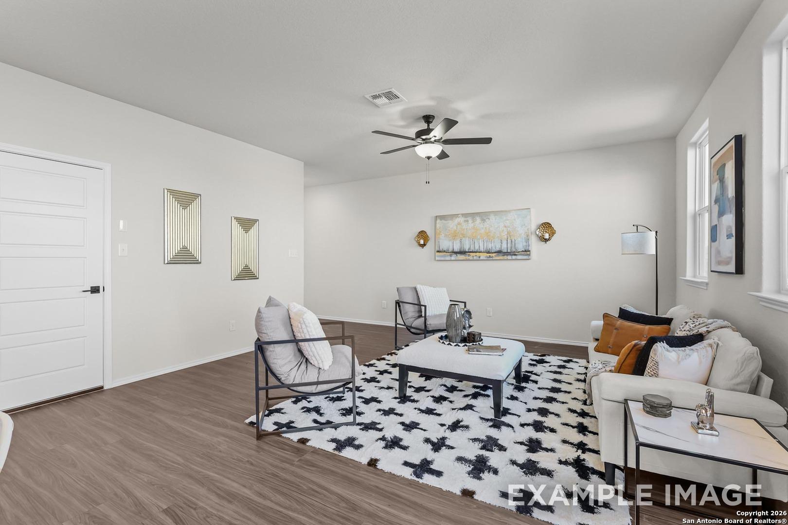 Modern living room with beige sofa, armchairs, ceiling fan, and abstract art in Davidson Homes The Trinity B, San Antonio, Texas