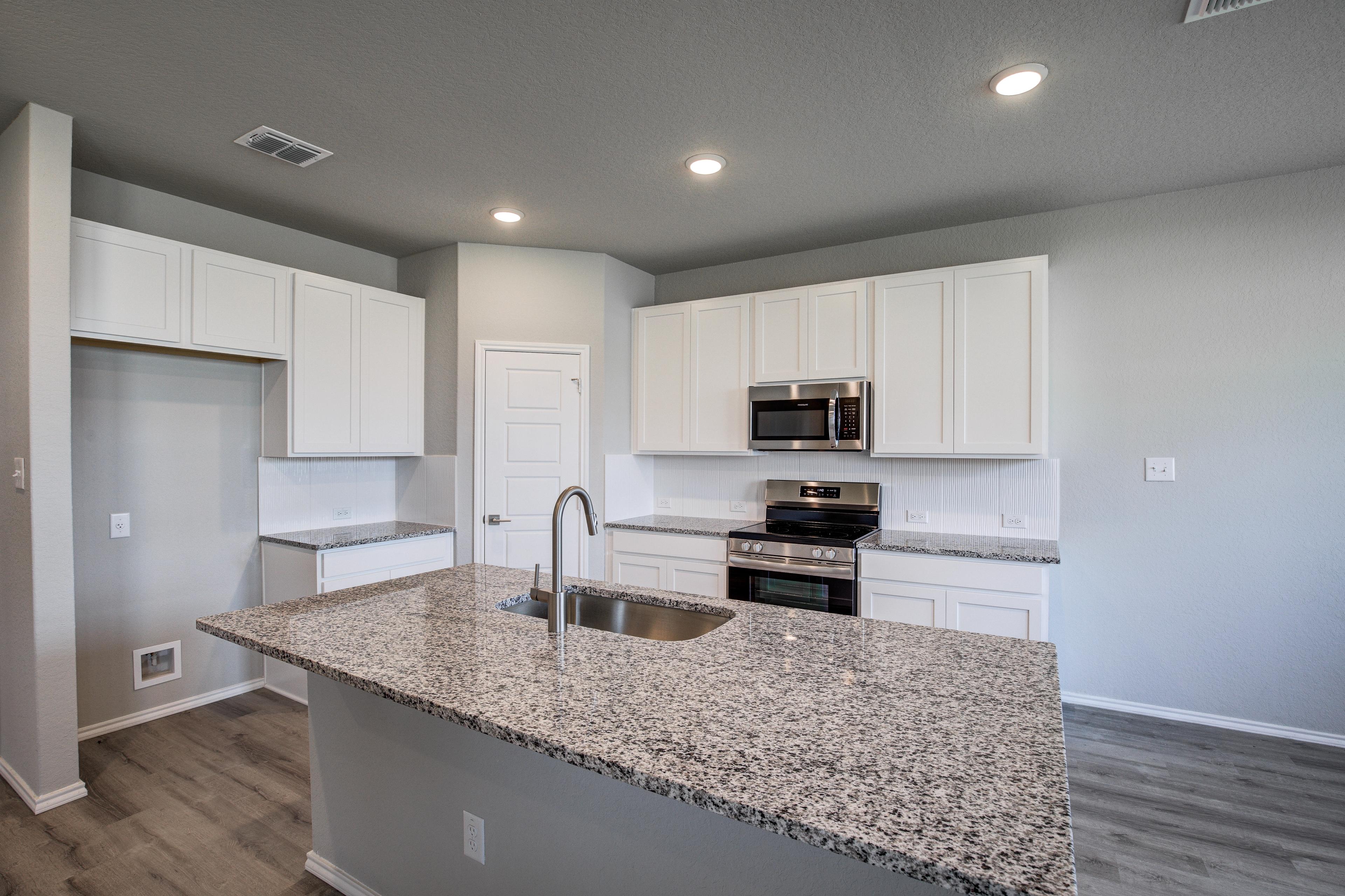 Modern kitchen in The Asheville home with white cabinets, granite island sink, stainless appliances, gray walls