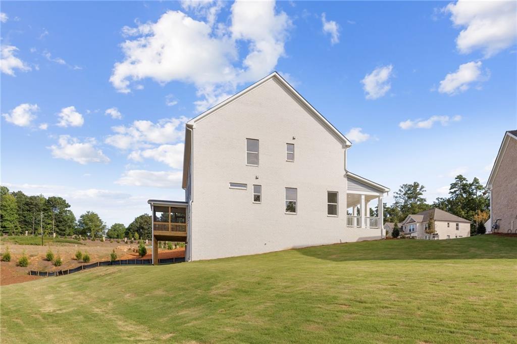Two-story white Hampton C home exterior with side deck, porch, and lush green yard in Melody Lakeside Estates, Buford, Georgia