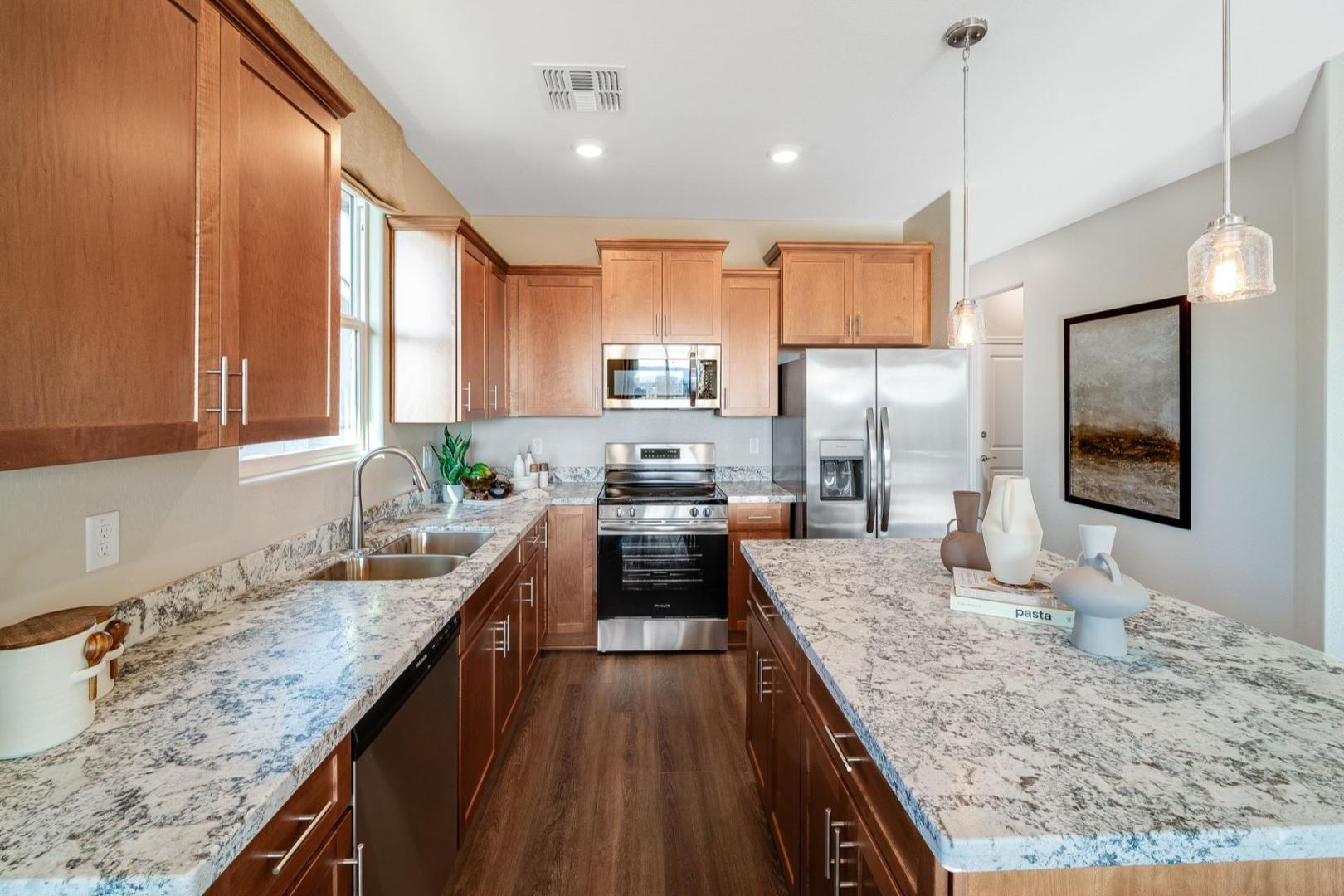 Spacious kitchen in The Savannah B by Davidson Homes featuring warm oak cabinets, granite counters, and stainless appliances