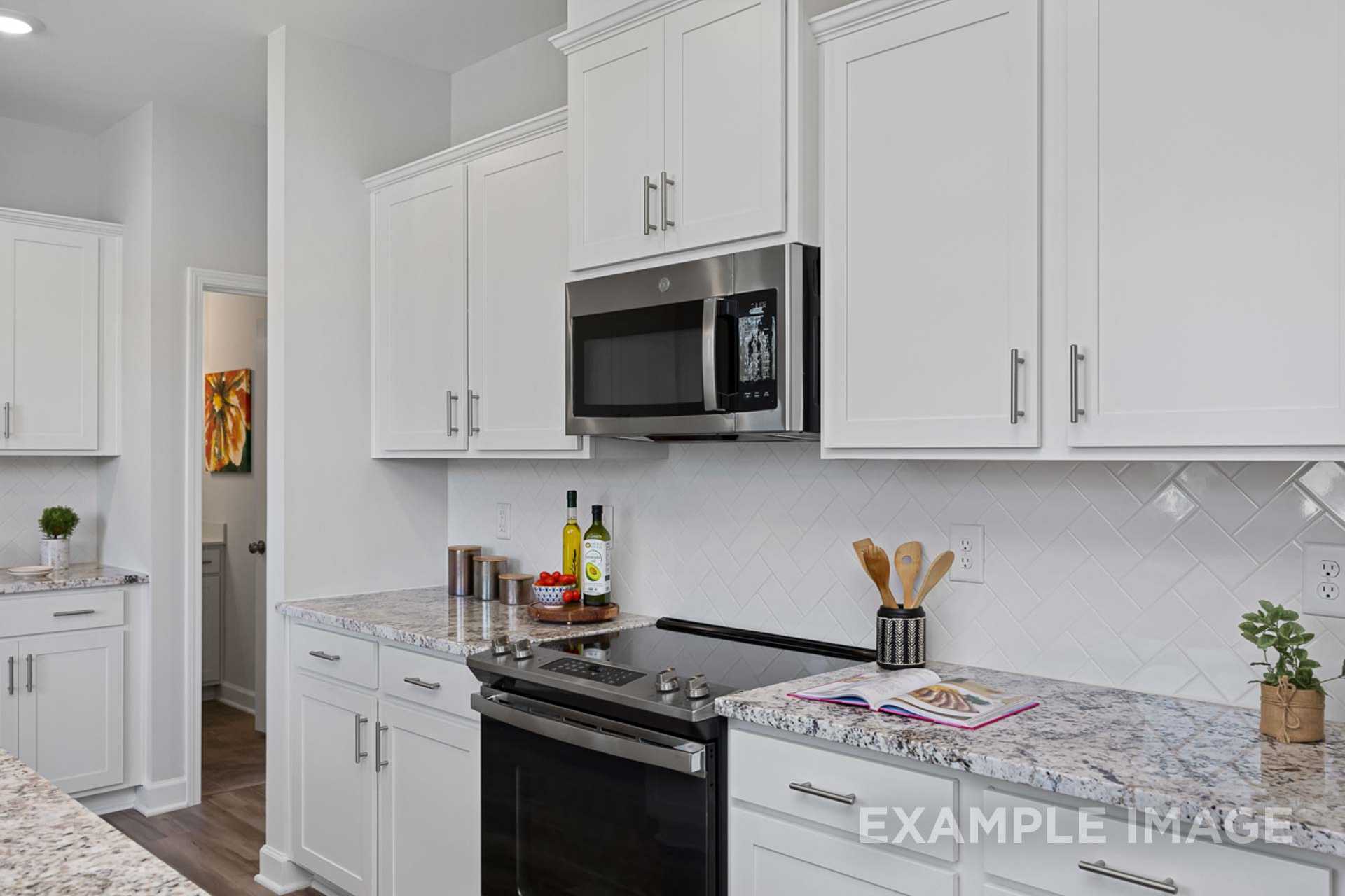 Modern kitchen in The Carter B by Davidson Homes featuring white shaker cabinets, stainless steel appliances, and quartz countertops