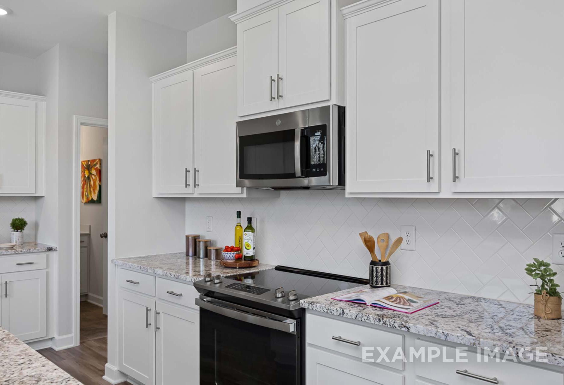 Modern kitchen in The Carter B by Davidson Homes featuring white shaker cabinets, stainless steel appliances, and quartz countertops