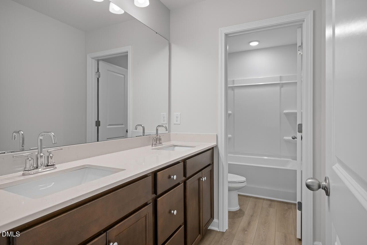 Modern bathroom with double vanity, quartz countertops, and tub-shower combo in The Hickory II B home in Lillington, NC.