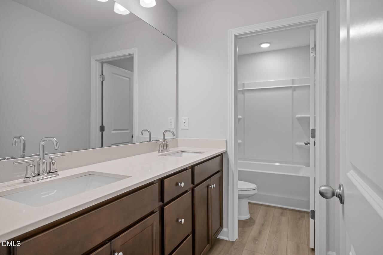 Modern bathroom with double vanity, quartz countertops, and tub-shower combo in The Hickory II B home in Lillington, NC.