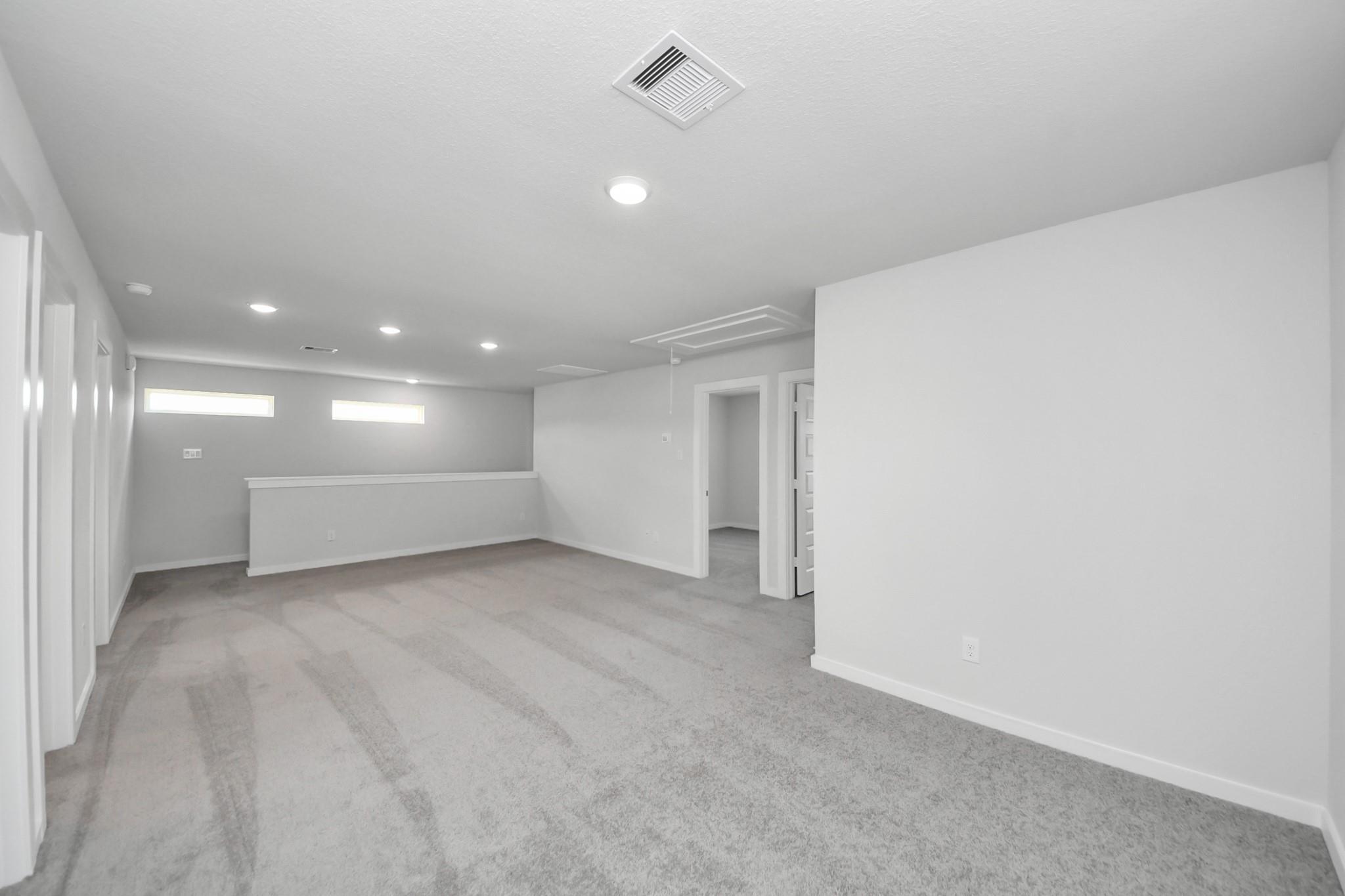 Spacious upstairs game room with plush carpeting in The Brazos F floor plan, Liberty Estates, Cleveland, Texas.
