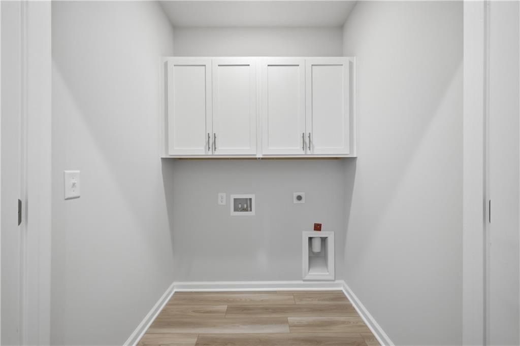 Laundry room with white cabinets, wood-look flooring, and washer connections in Davidson Homes' The Oconee B, Canton, Georgia