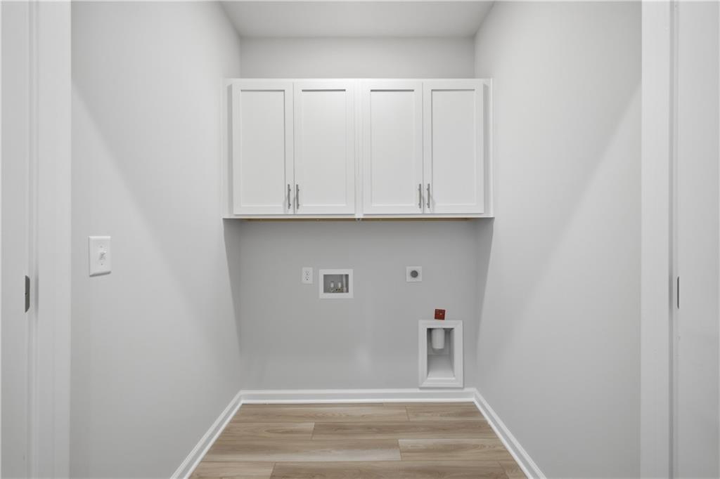 Laundry room with white cabinets, wood-look flooring, and washer connections in Davidson Homes' The Oconee B, Canton, Georgia