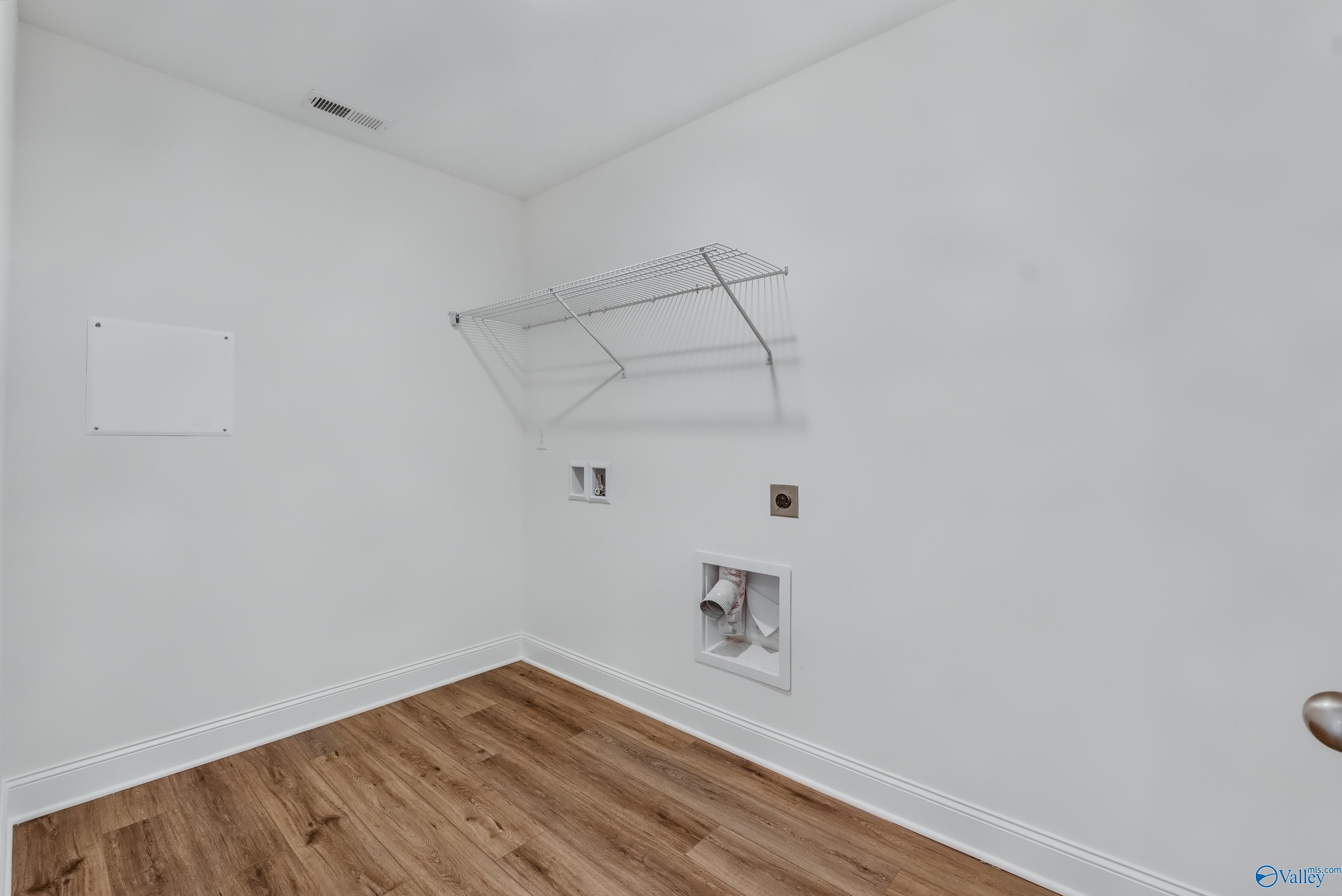 Spacious laundry room with wire shelving, washer/dryer hookups, and luxury vinyl plank flooring in Davidson Homes The Shelby A, Arab, Alabama