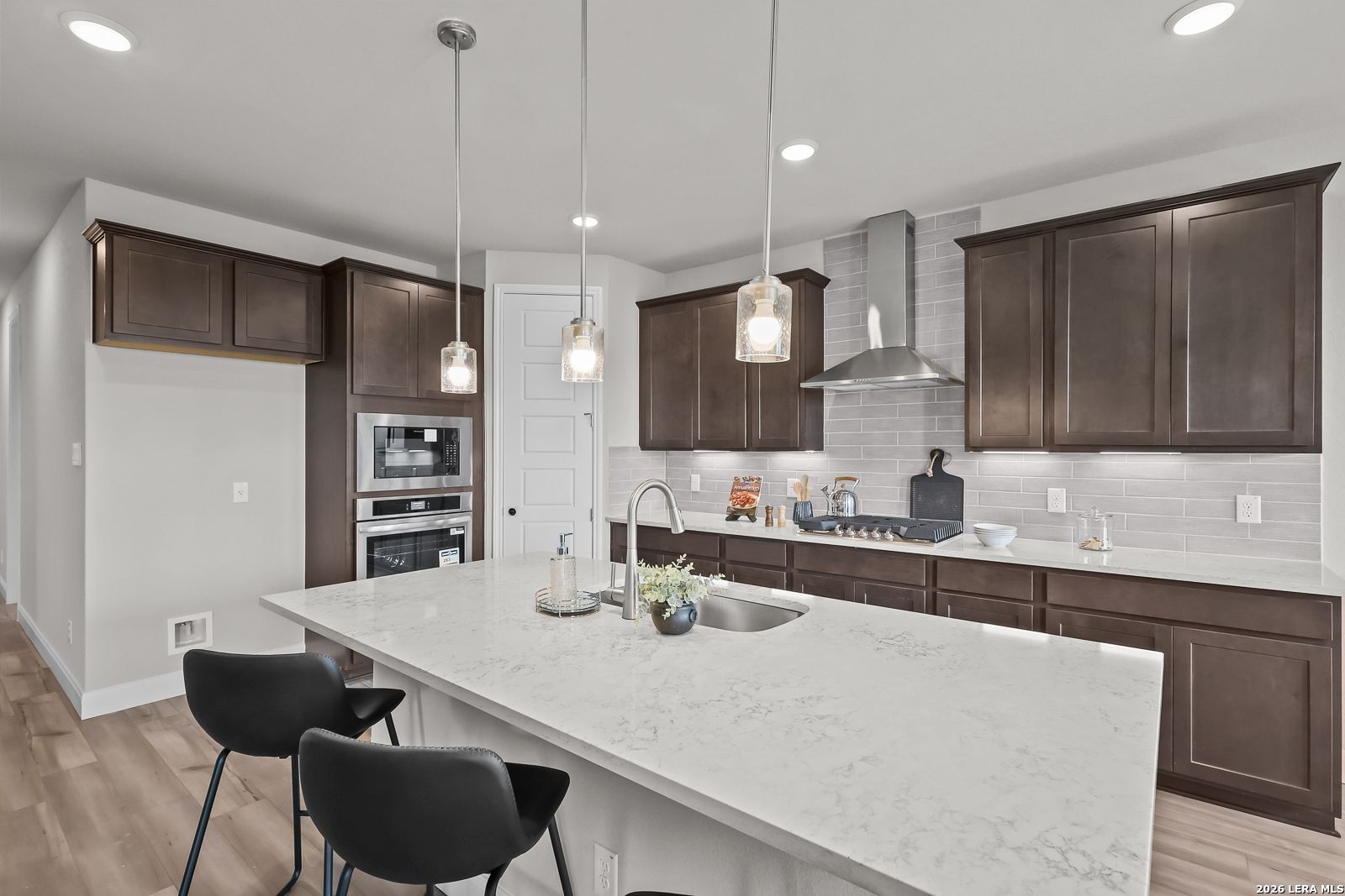 Modern kitchen featuring quartz island, dark wood cabinets, stainless steel appliances in Davidson Homes The Rockford G, Ladera, San Antonio