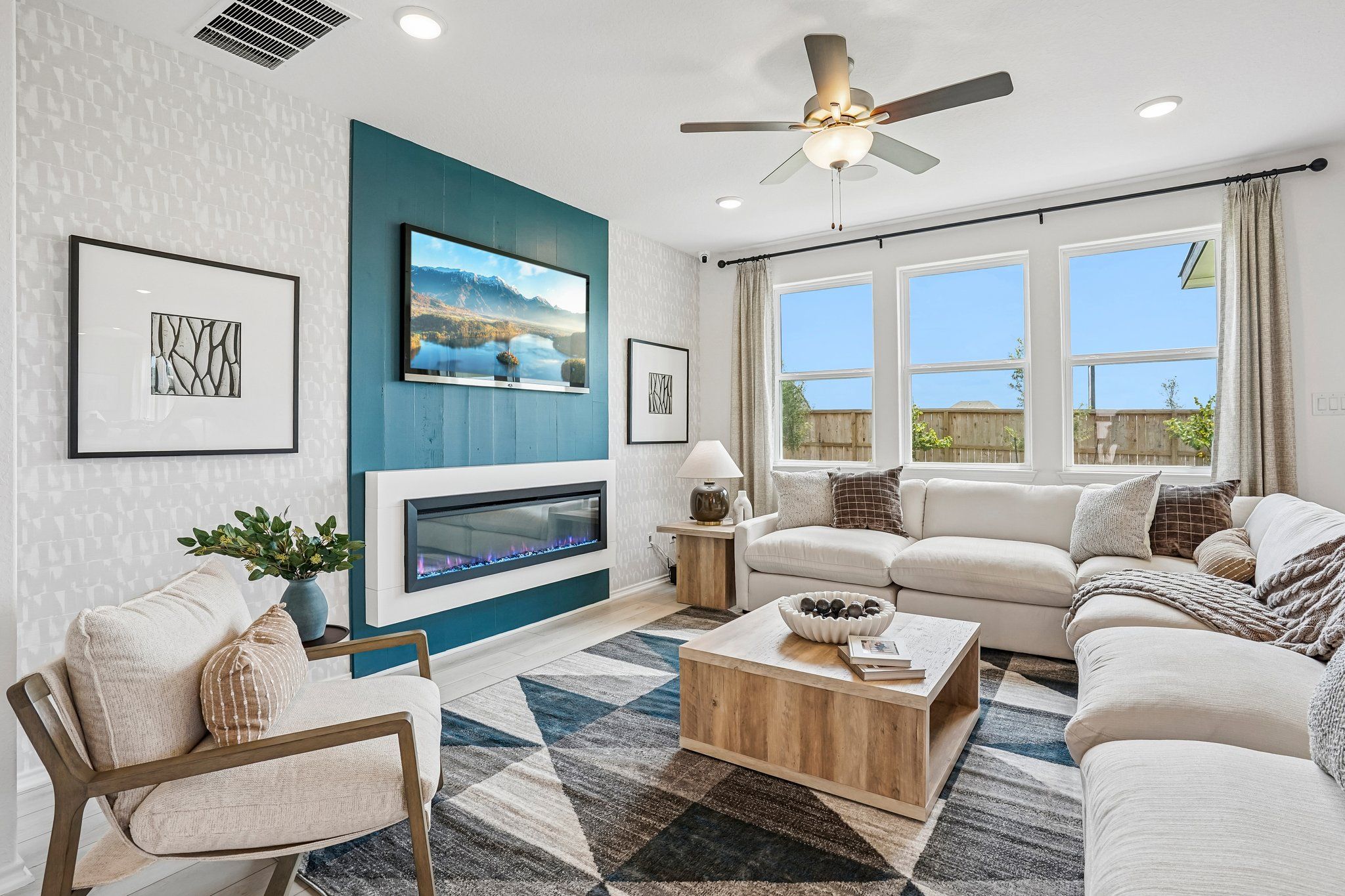 Modern living room at Morgan Meadows in San Antonio, Texas featuring a blue accent wall, electric fireplace, and sectional.