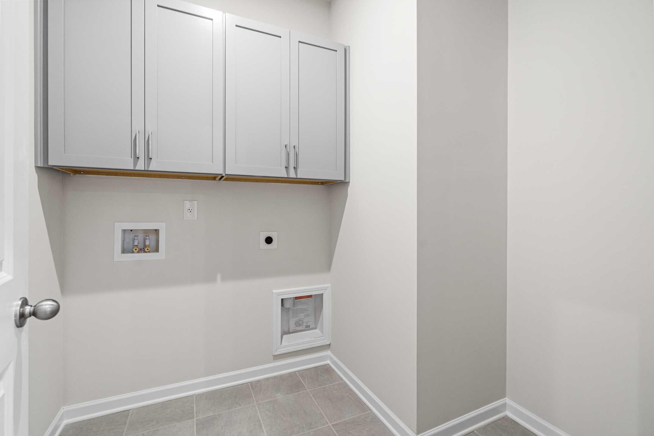 Spacious laundry room in The Glenwood A with white upper cabinets, washer dryer hookups, neutral walls, and tile flooring