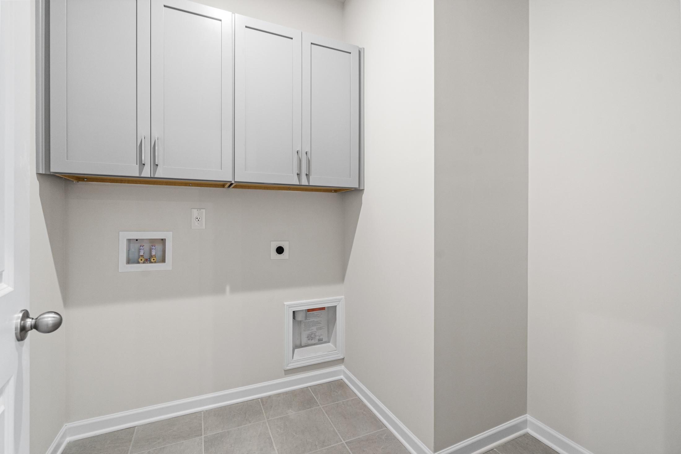 Spacious laundry room in The Glenwood A with white upper cabinets, washer dryer hookups, neutral walls, and tile flooring