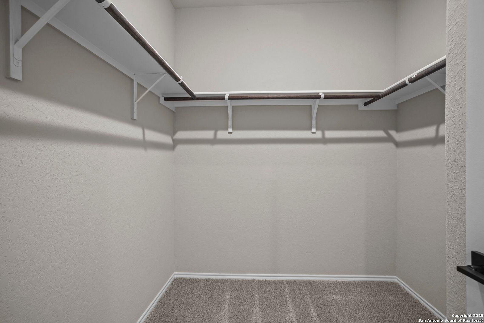 Spacious walk-in closet with wood shelving and hanging rods in Davidson Homes The Douglas F, Comanche Ridge, San Antonio