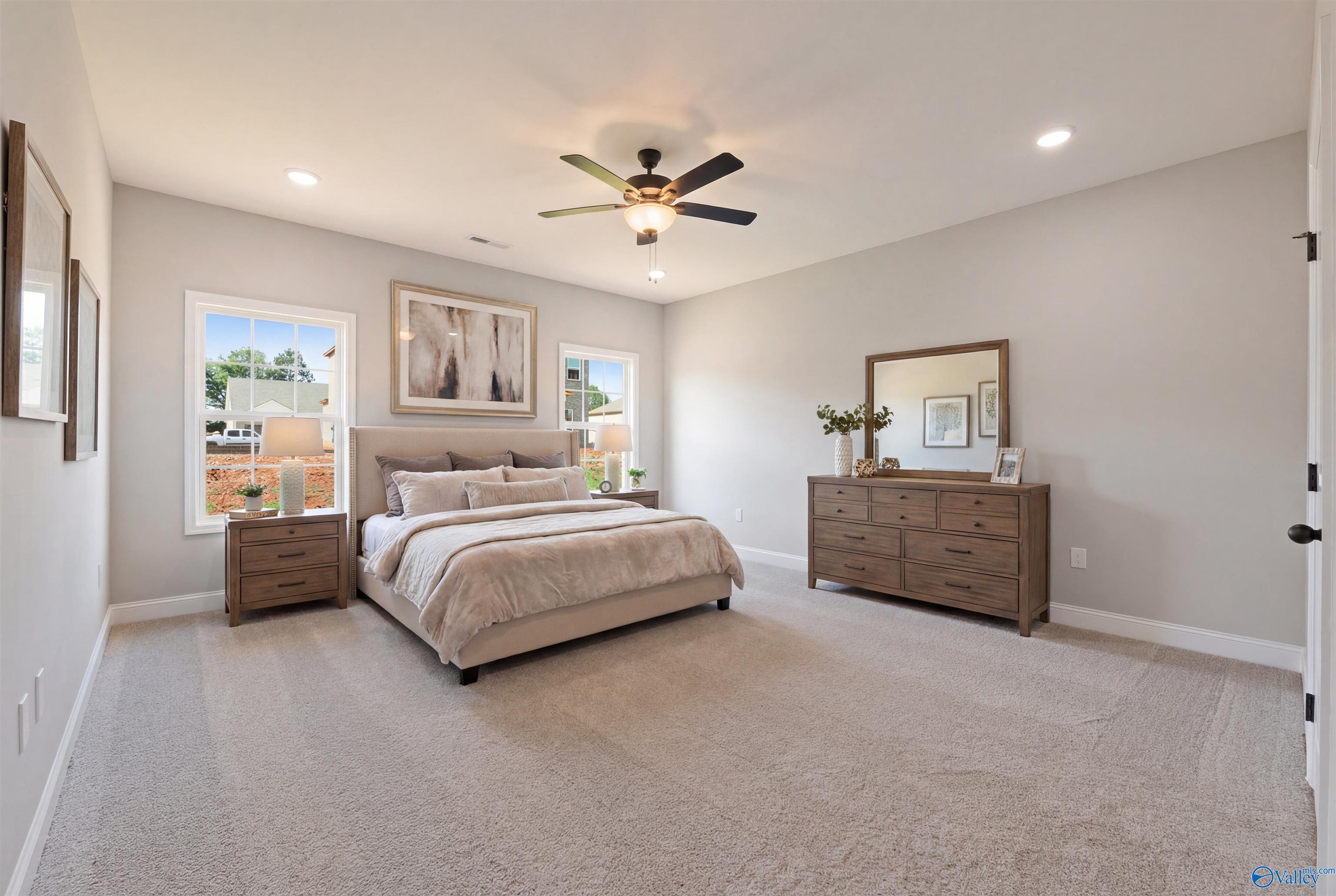 Elegant master bedroom with king bed, wooden dresser, mirror, ceiling fan in The Rockford with Bonus by Davidson Homes, Toney, AL