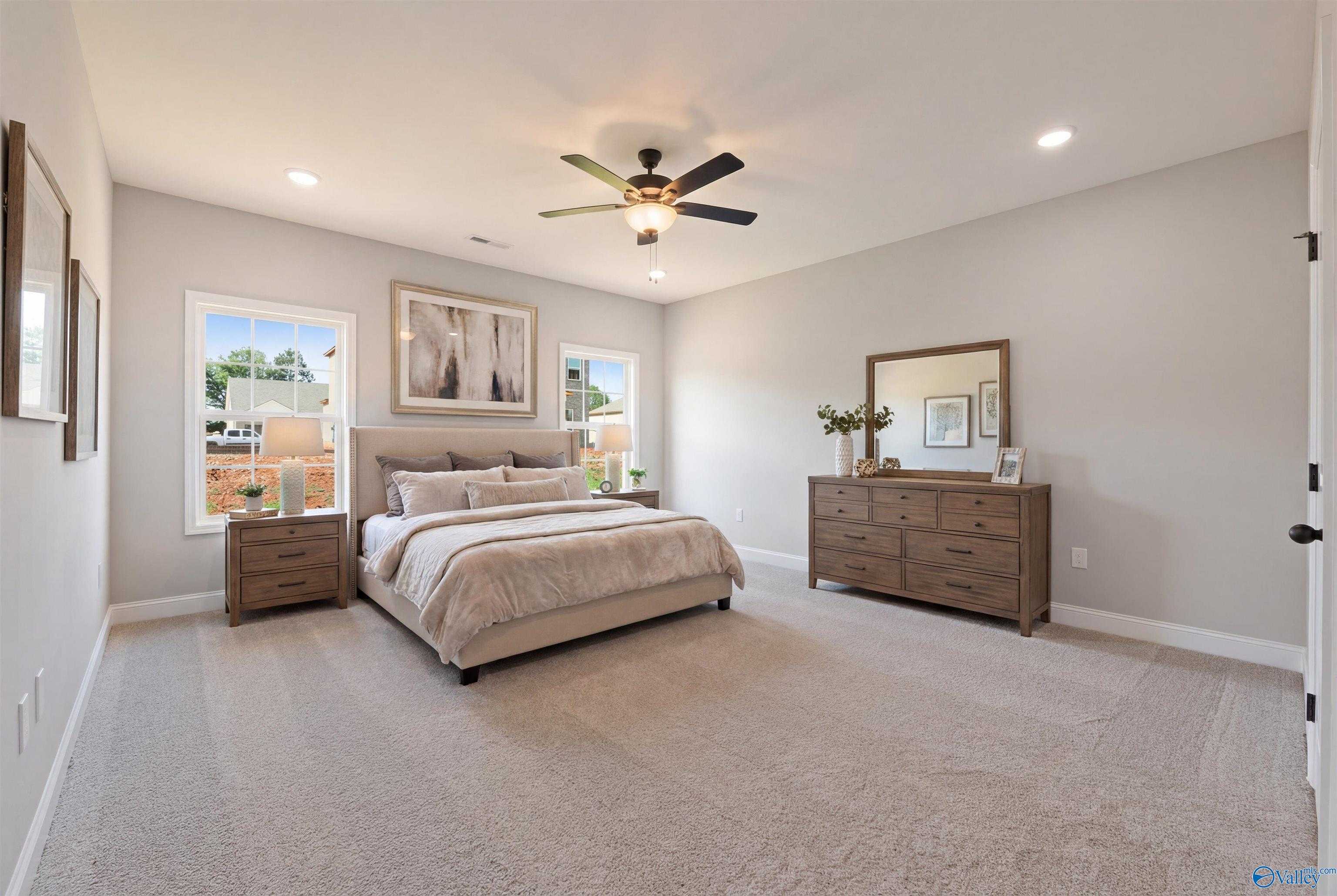 Elegant master bedroom with king bed, wooden dresser, mirror, ceiling fan in The Rockford with Bonus by Davidson Homes, Toney, AL