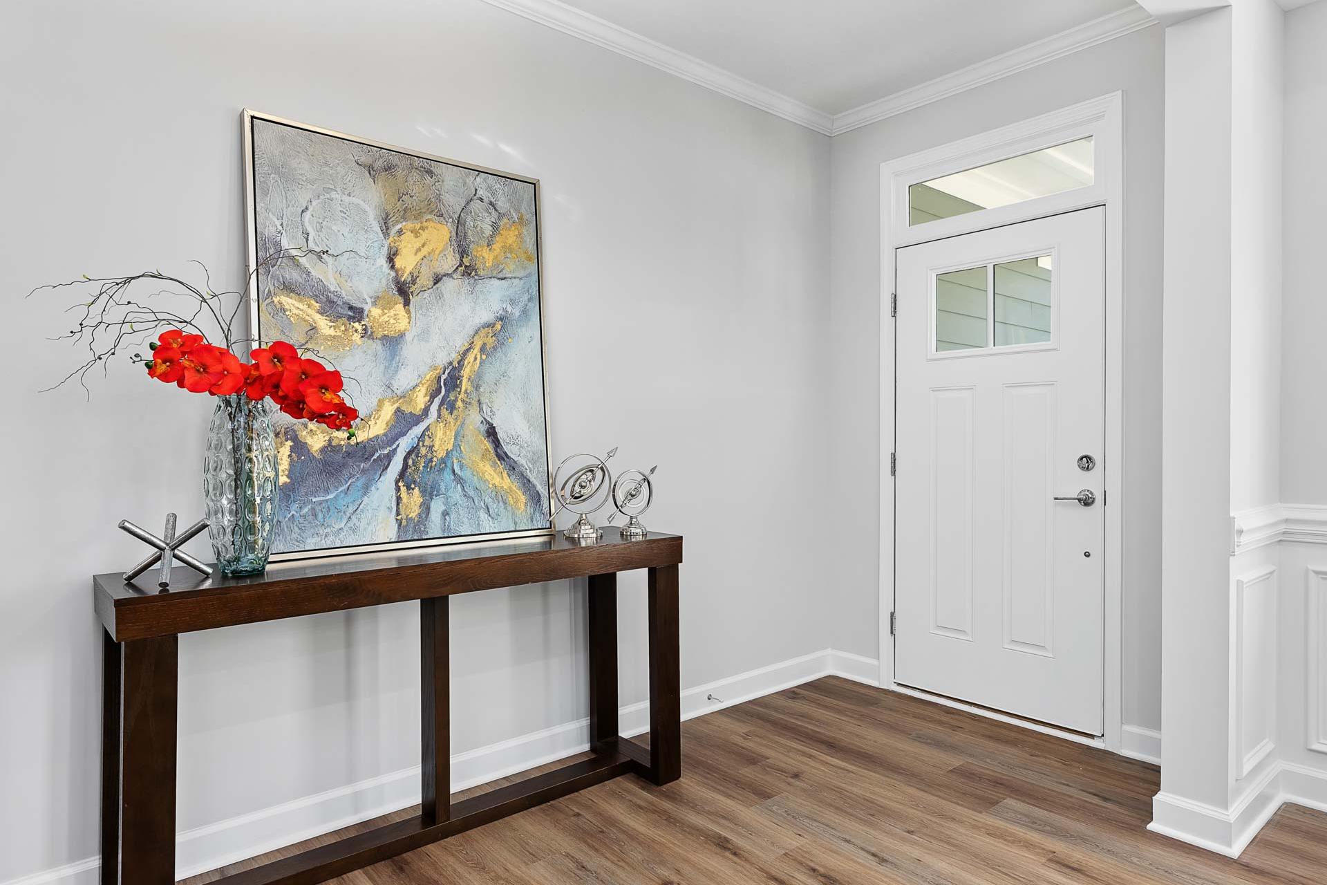 Elegant entryway in Glenmere home by Davidson Homes in Knightdale NC with console table red orchids abstract gold artwork white door