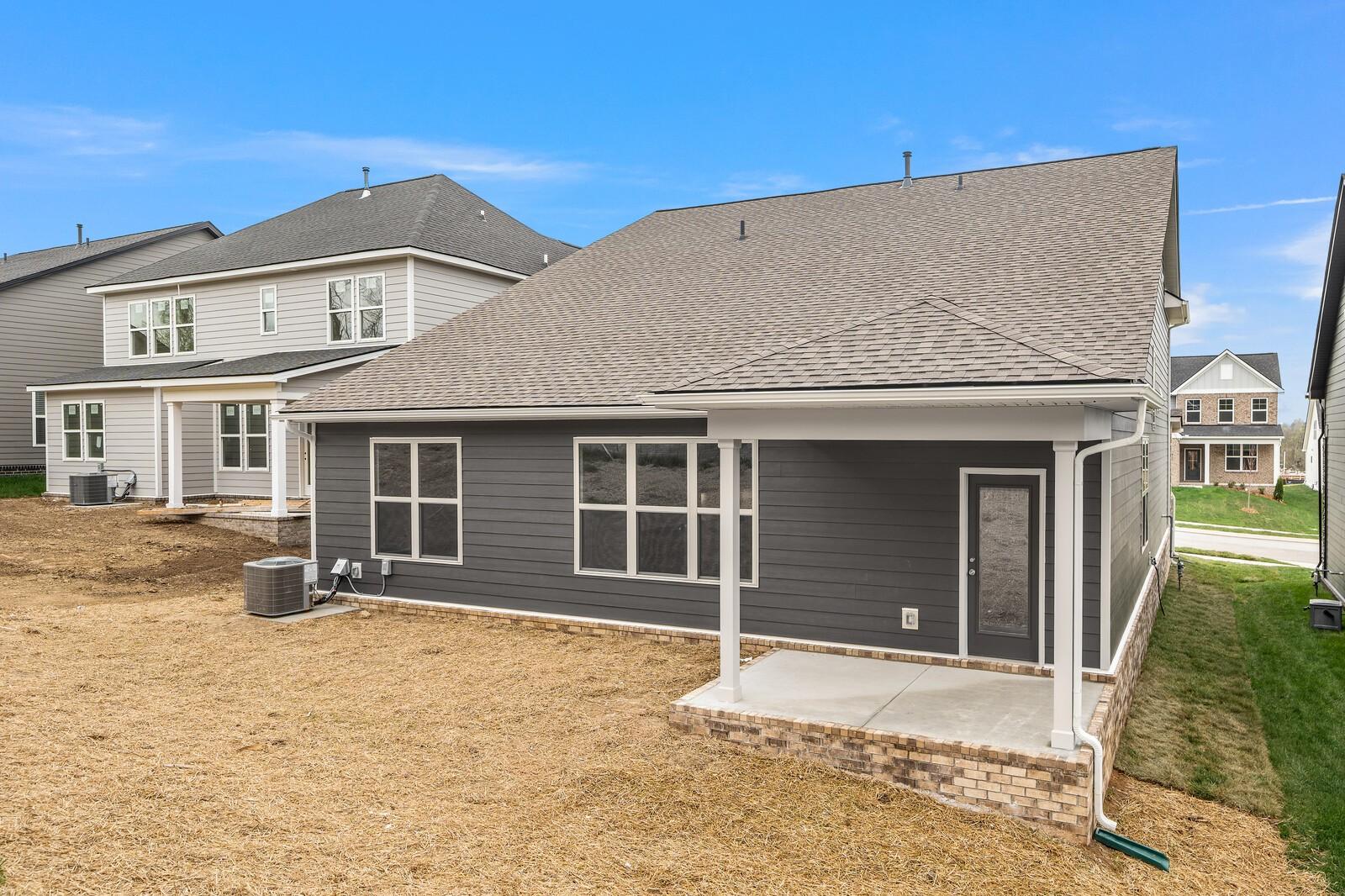 Modern two-story home exterior with gray siding, covered side porch, and windows in Woods Crossing, Gallatin, Tennessee