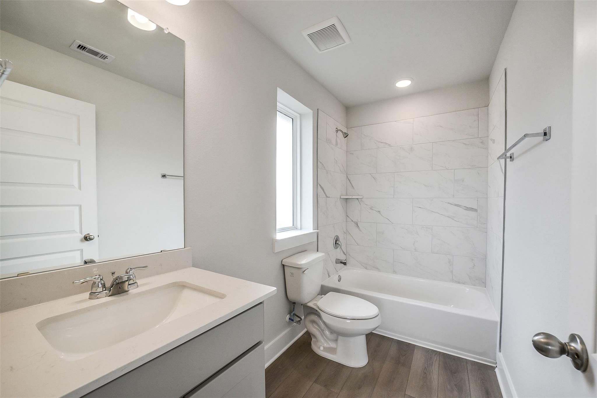 Modern bathroom with white subway tile shower-tub, gray vanity sink, mirror, and toilet in Davidson Homes The Philip B, Rosharon TX