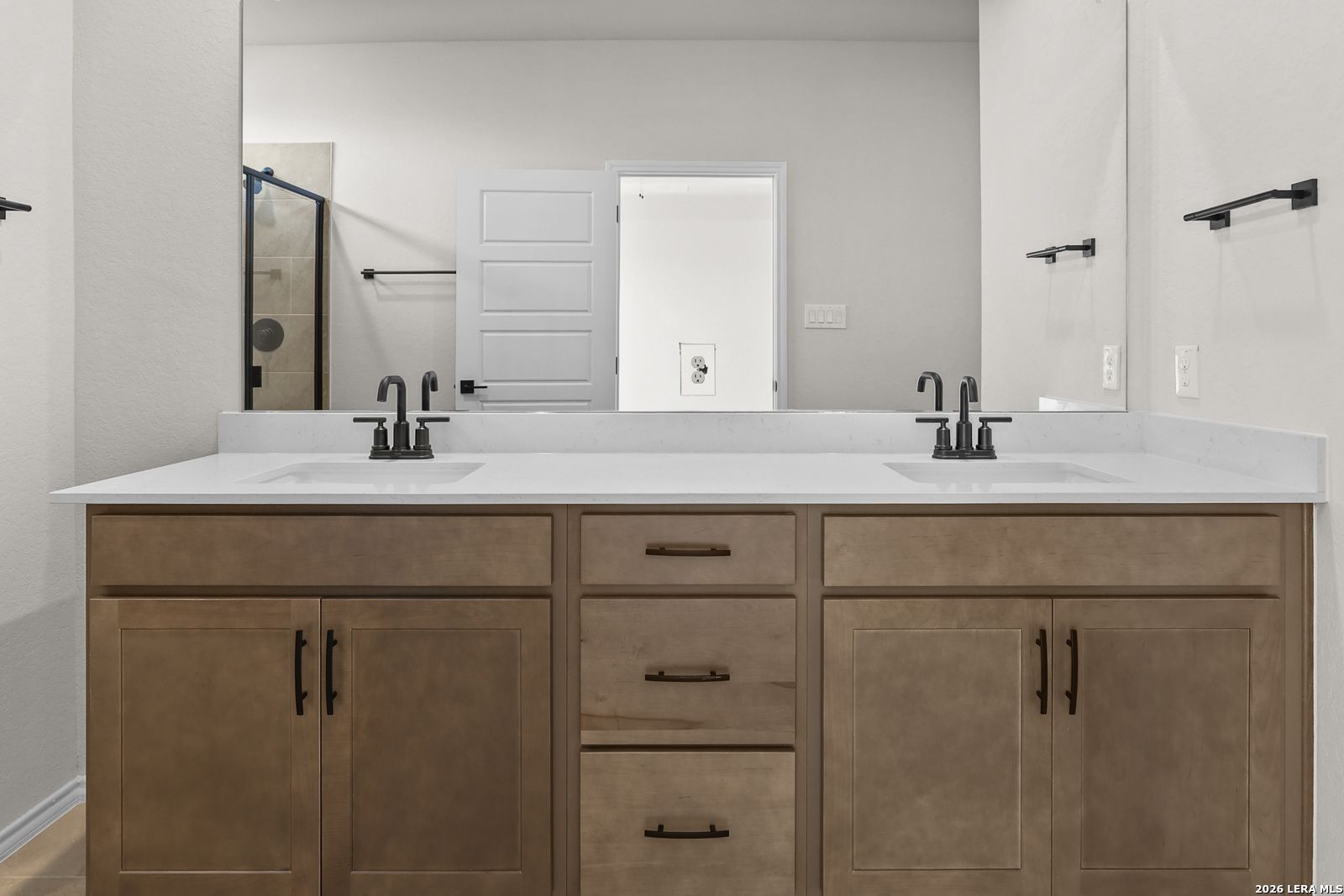 Dual vanity bathroom with white quartz countertops, wood cabinets, and matte black faucets in Davidson Homes Glenwood E, San Antonio
