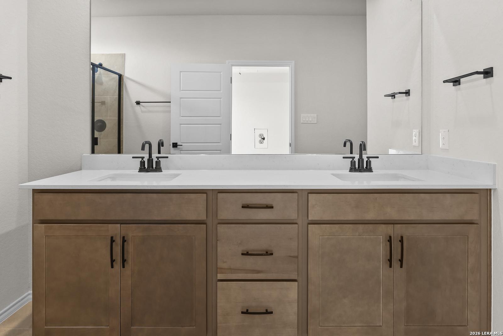 Dual vanity bathroom with white quartz countertops, wood cabinets, and matte black faucets in Davidson Homes Glenwood E, San Antonio