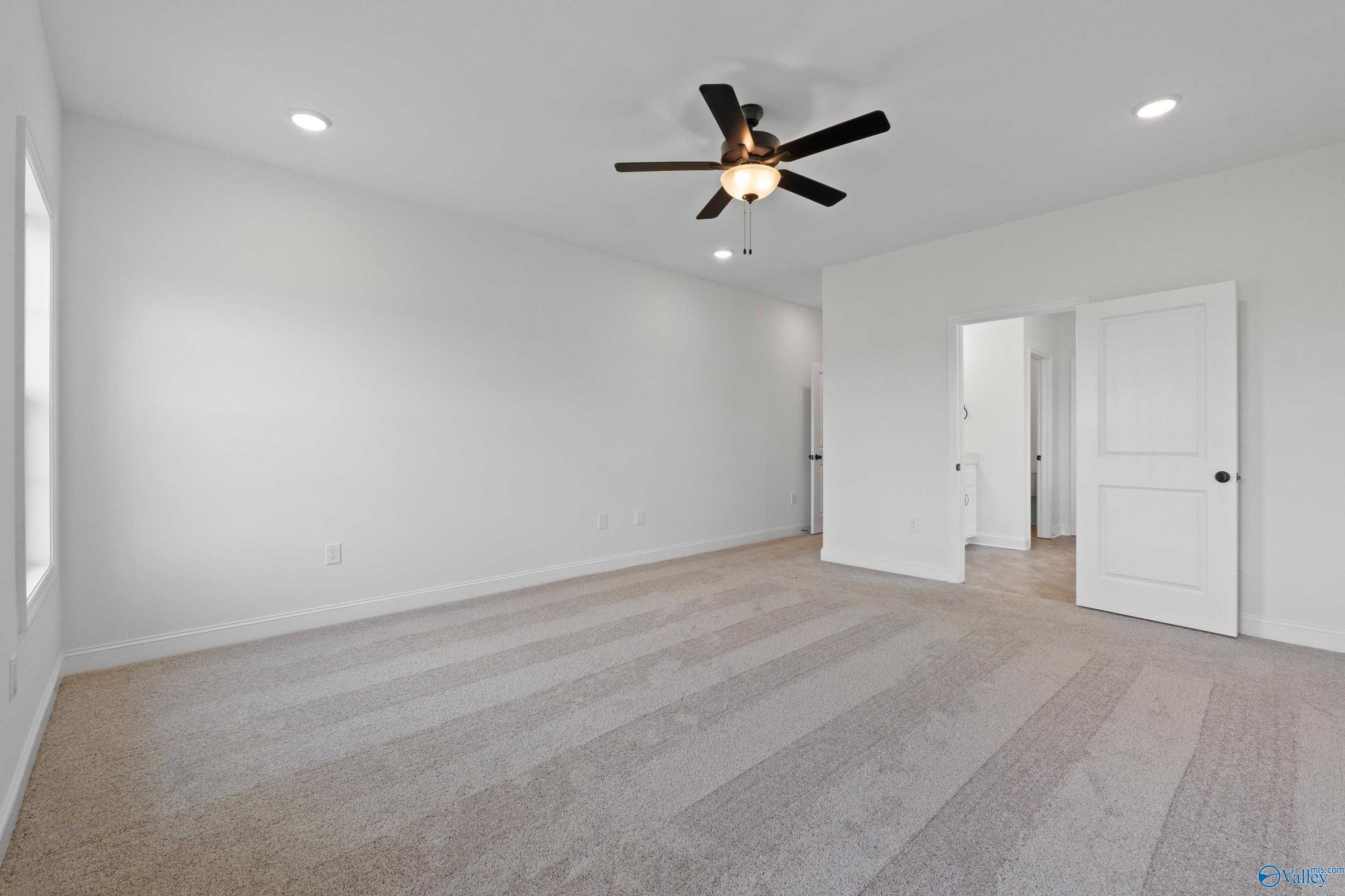 Spacious carpeted bedroom with ceiling fan, recessed lights, and white doors in Davidson Homes The Rockford B, Toney, Alabama
