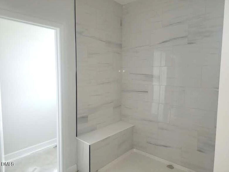 Tiled walk-in shower with built-in bench seat in owner's bath of Davidson Homes The Crawford D, Angier, North Carolina