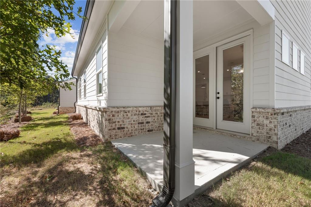 Covered patio with double glass doors on white brick-accented Davidson Homes The Daphne B in Kelly Preserve, Loganville, Georgia