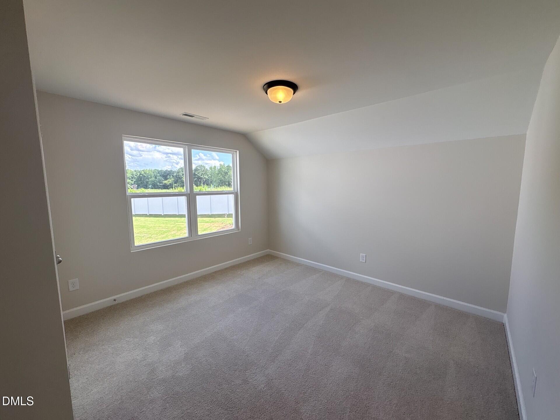Spacious carpeted bedroom with vaulted ceiling and natural light in The Ash C floor plan at Woodland Crossing, Zebulon, NC.