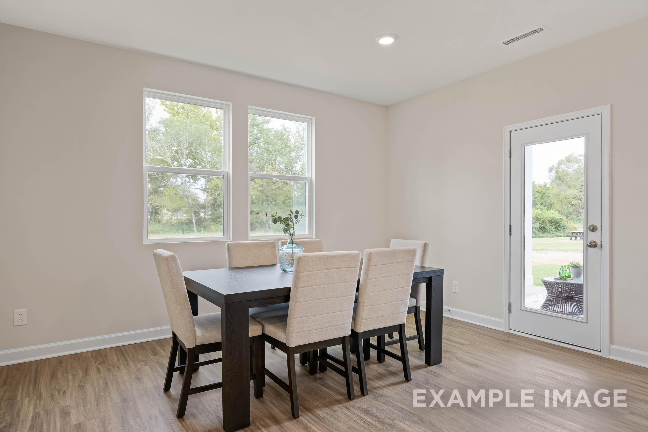 Spacious dining room in The Preston B with wooden table, beige chairs, large windows, French doors to patio, hardwood floors