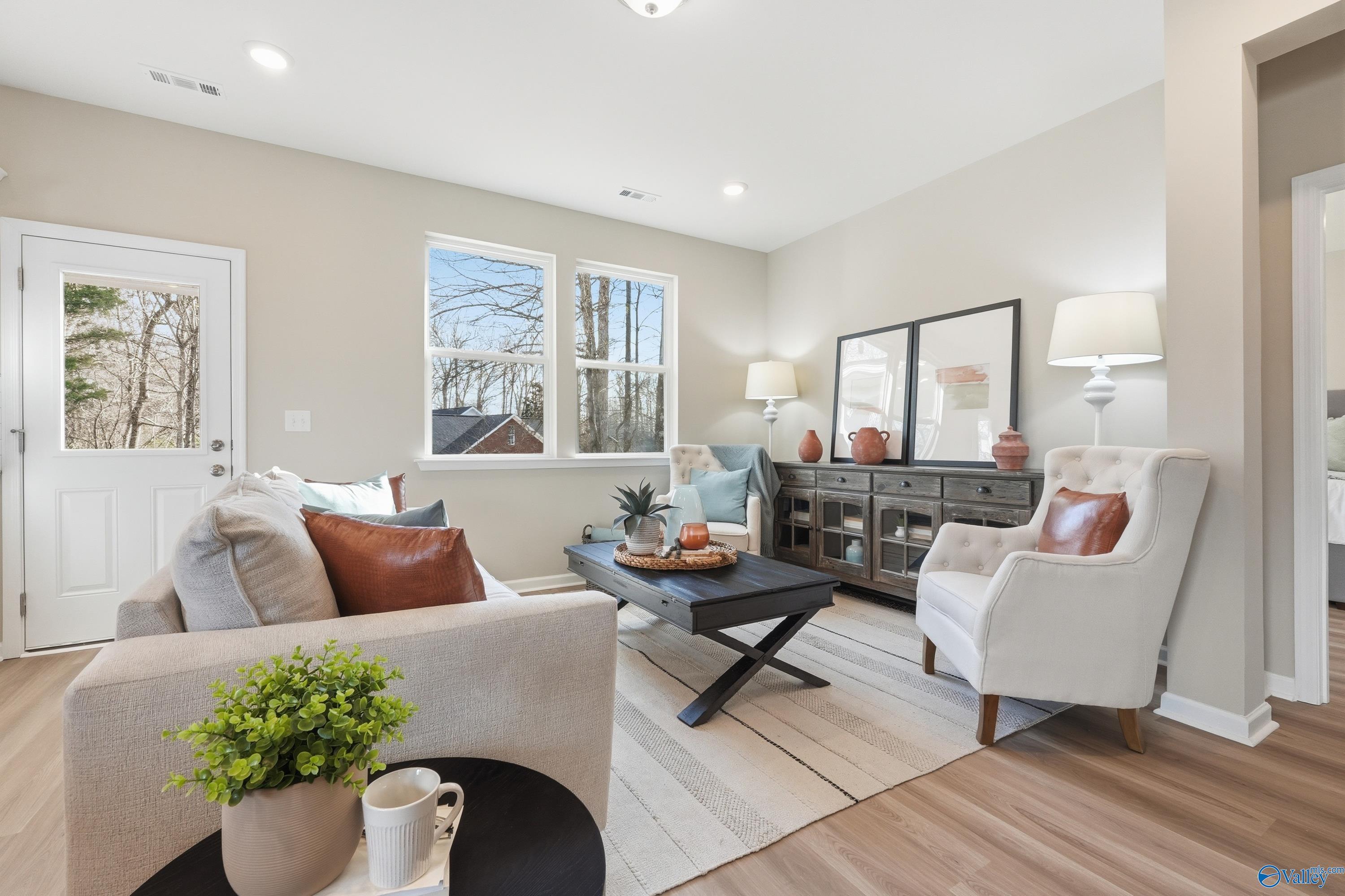 Cozy living room with neutral beige walls, plush sofa, armchair, coffee table, and hardwood floors in Davidson Homes The Polaris, Fayetteville, TN