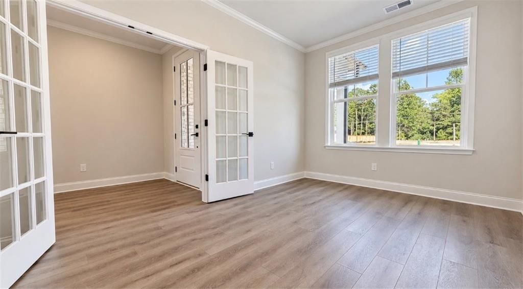 Bright flex room with French glass doors, luxury vinyl plank flooring, and large windows in Davidson Homes The Harrison H, Hoschton, GA