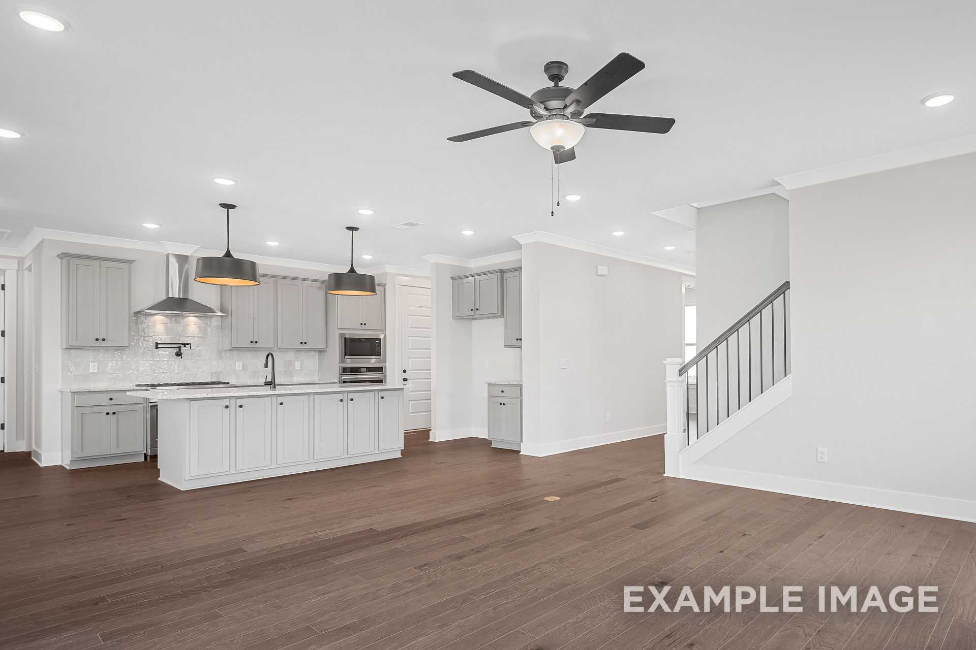 Spacious open-concept kitchen in The Hathaway by Davidson Homes with white shaker cabinets, large island, pendant lights, and hardwood floors