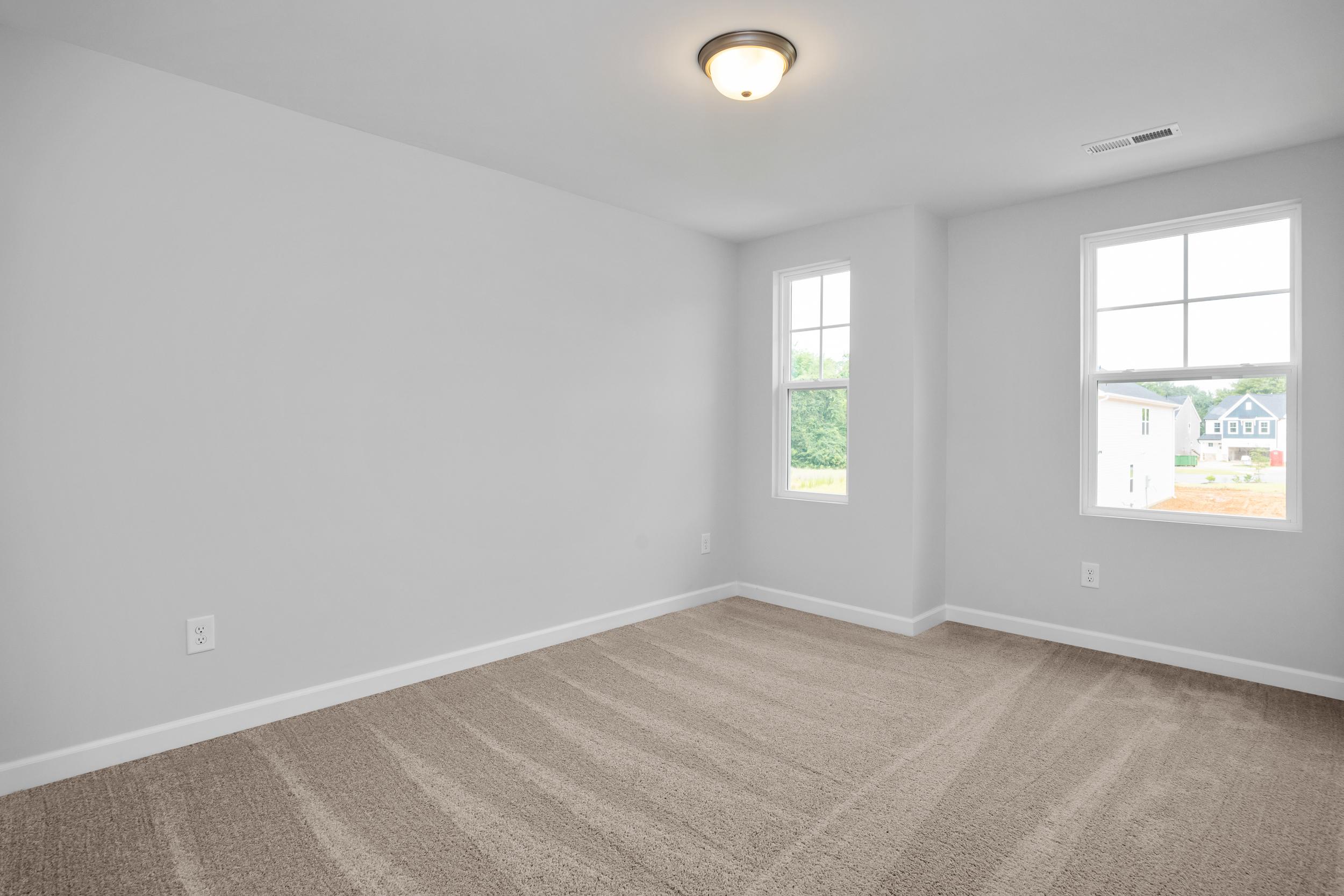 Spacious bedroom with neutral carpet and natural light in The Durham home design by Davidson Homes in Lillington, NC.
