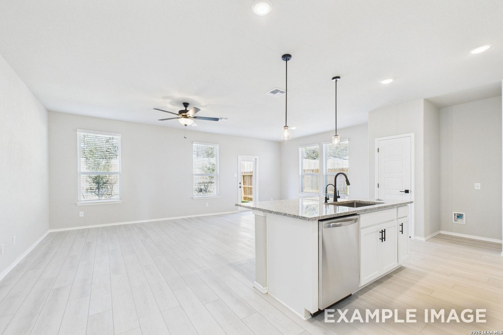 Open-concept kitchen and living area with granite island in The Charlotte B floor plan by Davidson Homes, San Antonio.