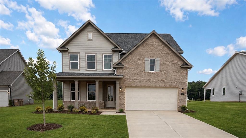 Two-story Hickory C floor plan by Davidson Homes with brick exterior, 2-car garage, and lawn in Wehunt Meadows, Hoschton, GA