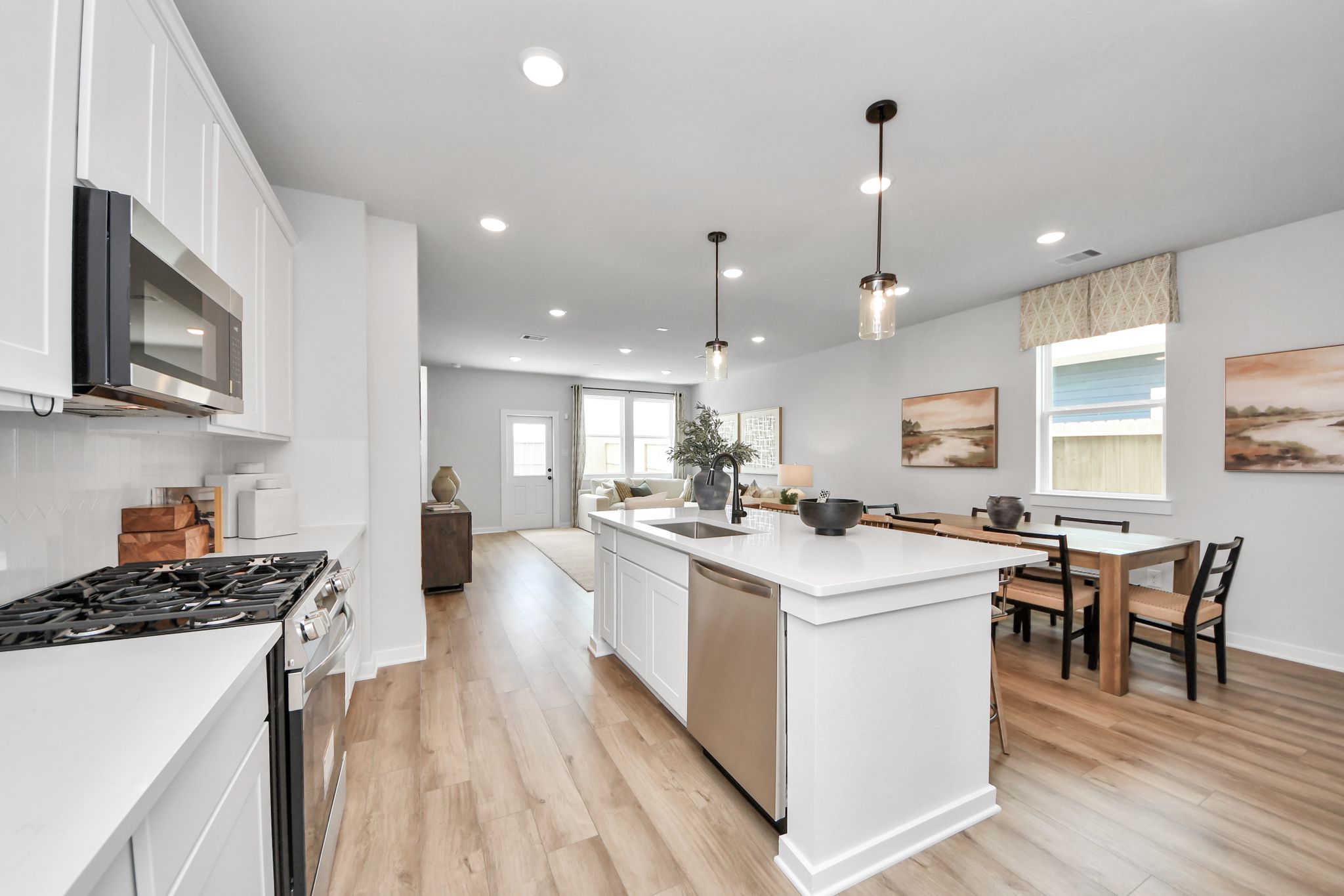 Modern open-concept kitchen at Robins Landing in Houston with white cabinetry, quartz island, and wood-style flooring.