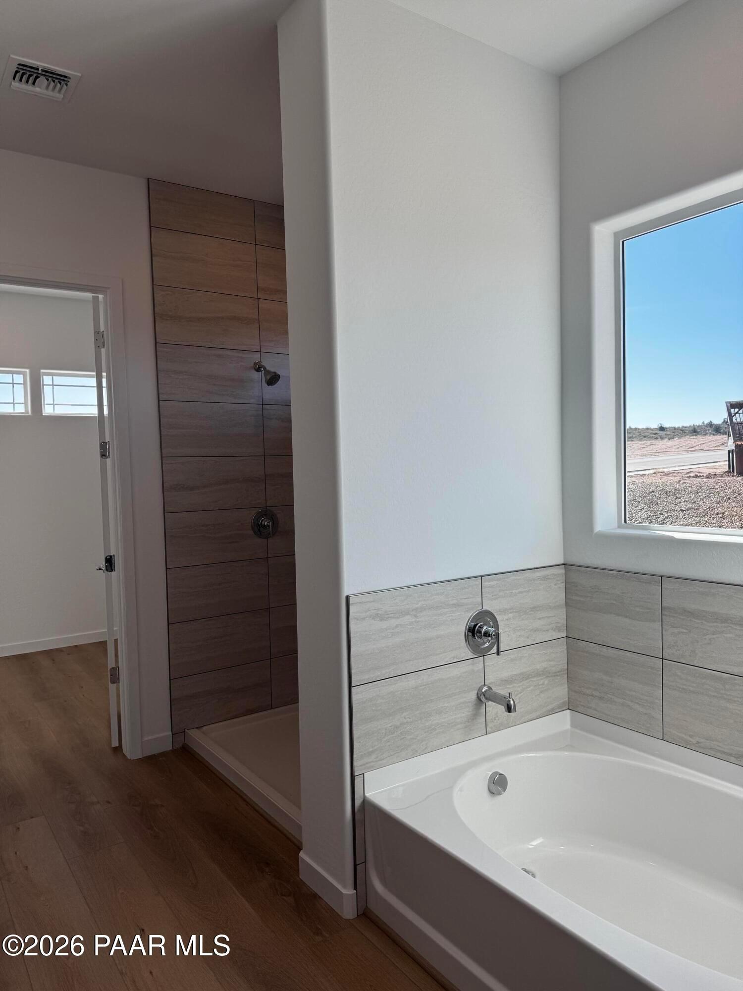 Modern master bathroom featuring soaking tub, walk-in shower with wood accents, and desert view in Davidson Homes The Blaze C, Prescott, Arizona