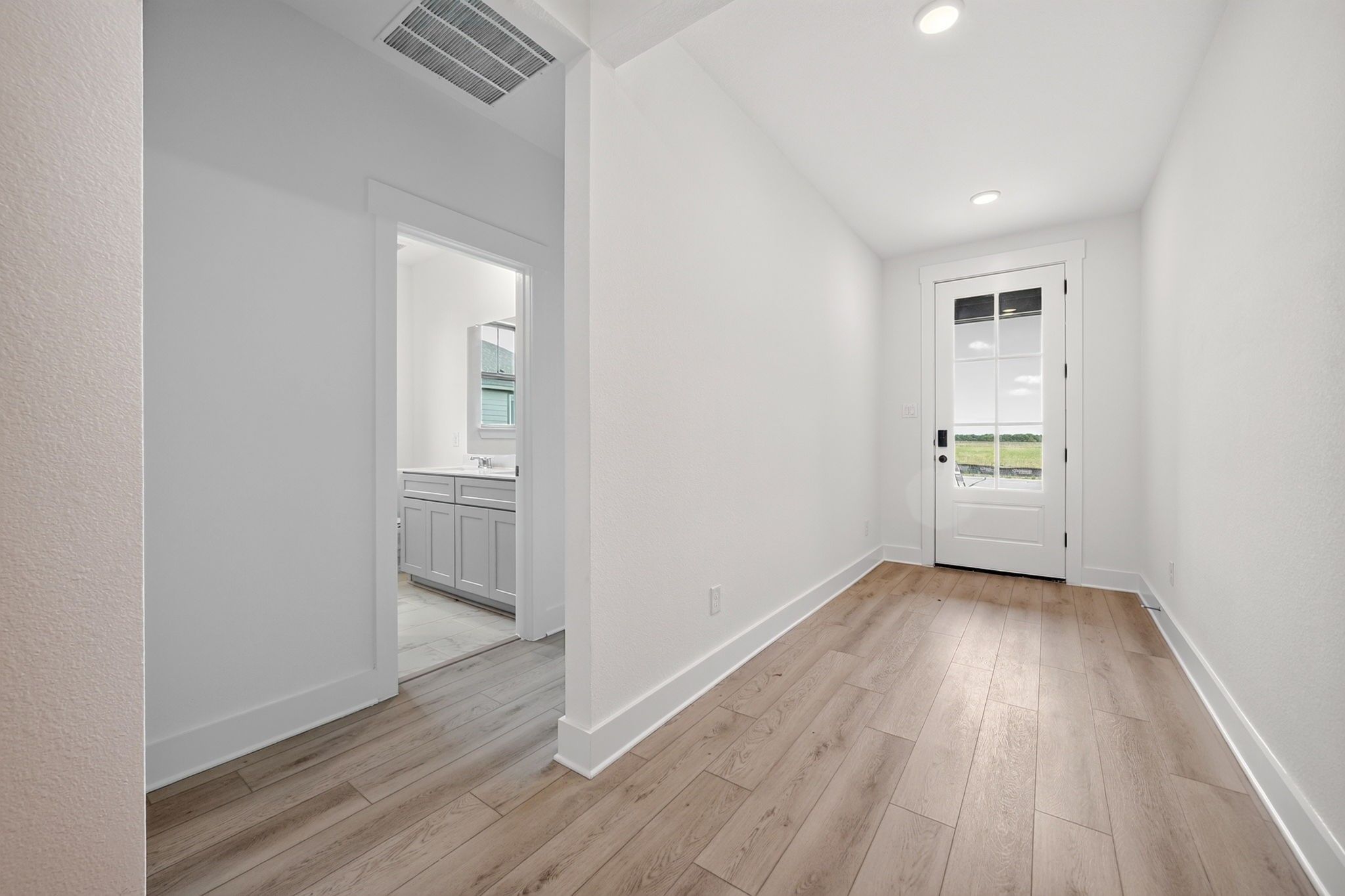 Bright entryway with wood-look flooring and glass-paneled front door in Davidson Homes The Holly F, Meadow Ridge Estates, Josephine, TX