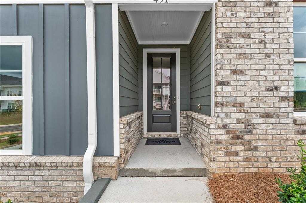 Welcoming front porch with dark glass door, gray siding, and beige brick on The Monroe A home in Stegall Village, Emerson, GA