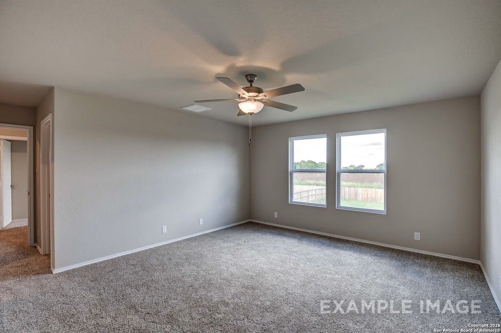 Spacious carpeted bedroom with ceiling fan, large windows overlooking fenced backyard in Davidson Homes The Murray K, San Antonio