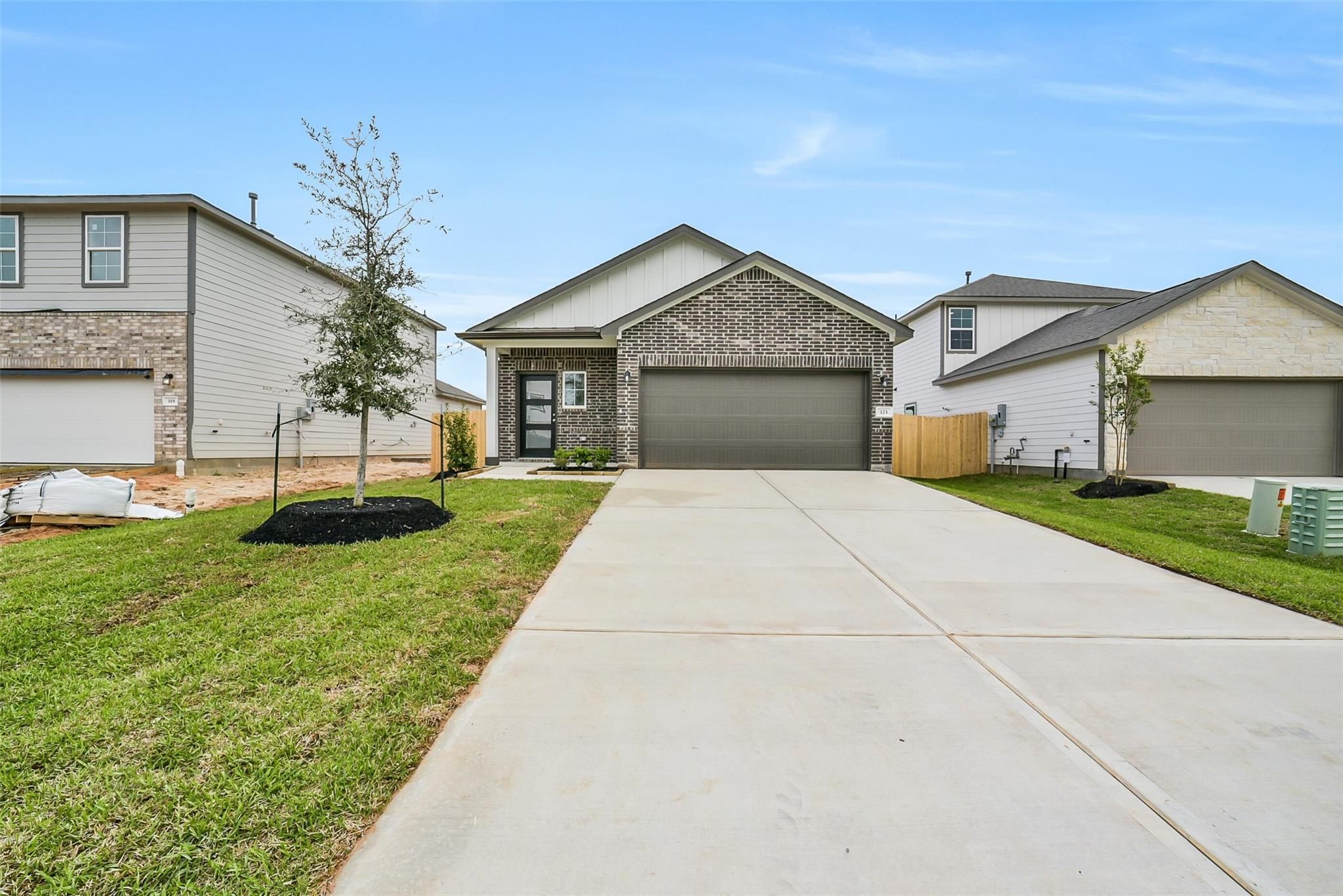 Modern single-story brick home with 2-car garage, driveway, and landscaped front yard in Caney Creek Place, Conroe, Texas