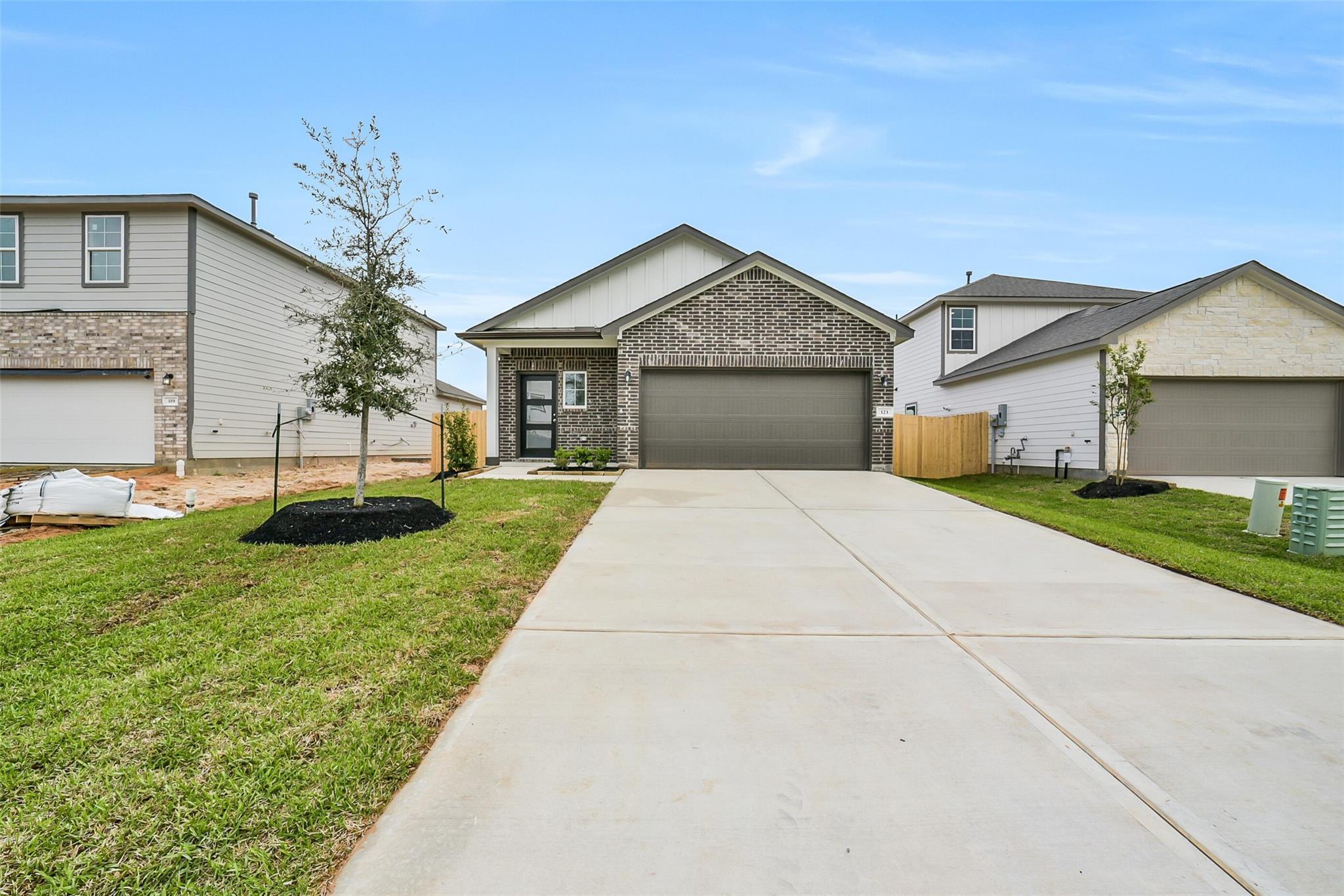 Modern single-story brick home with 2-car garage, driveway, and landscaped front yard in Caney Creek Place, Conroe, Texas