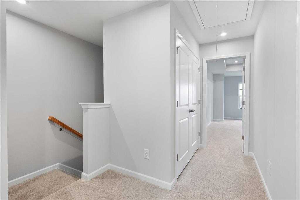 Bright upstairs hallway with white walls, beige carpet, double doors, and staircase in Davidson Homes The Durant A, Emerson, Georgia