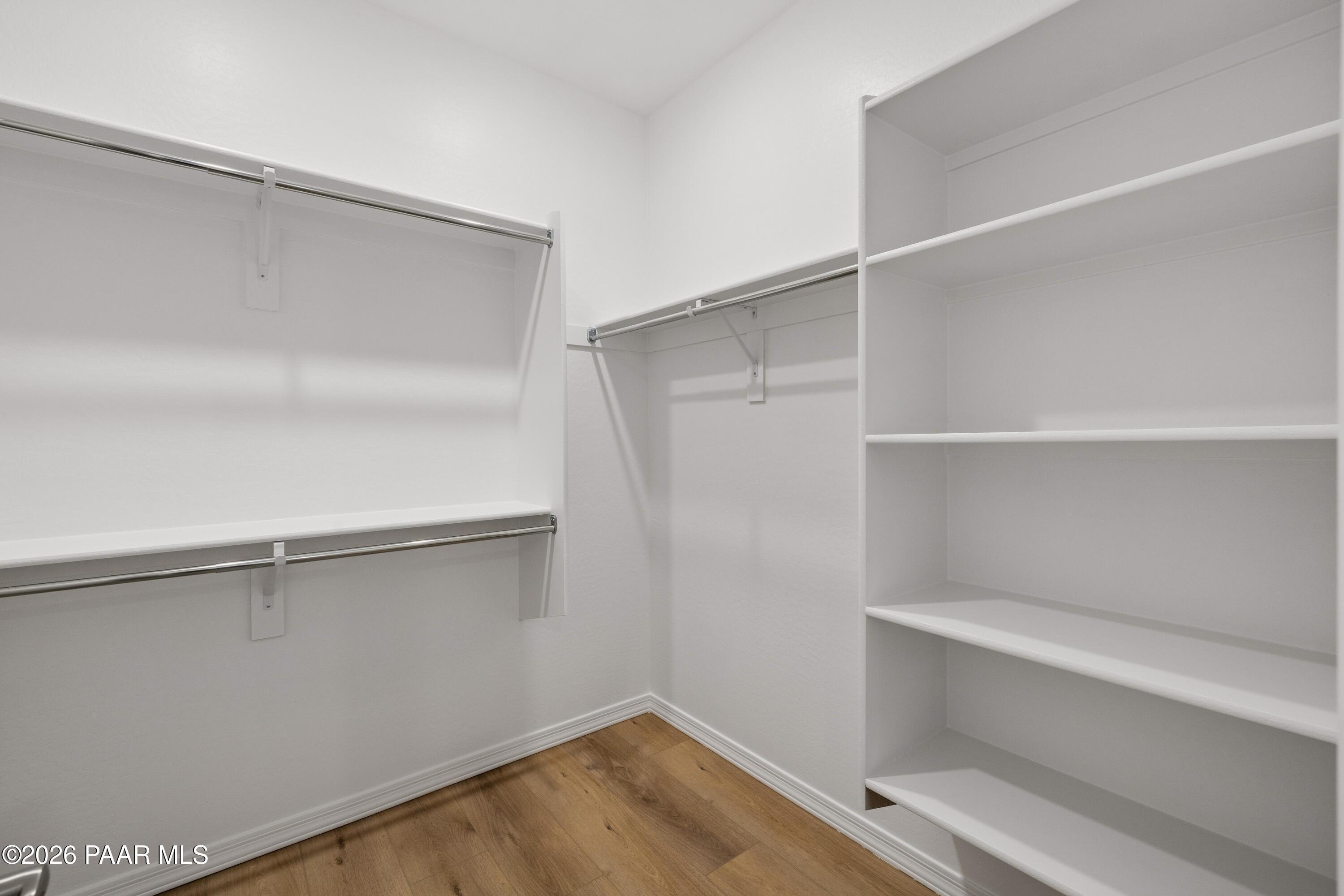 Spacious walk-in closet with white shelves and hanging rods in master suite of Davidson Homes The Harmony A, Prescott Valley, AZ