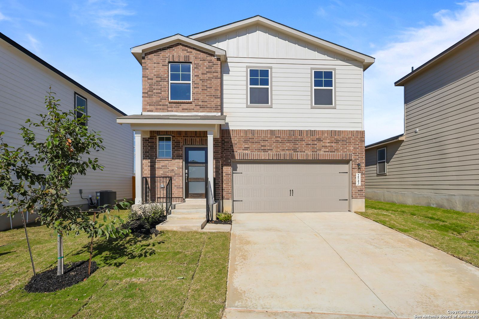 Two-story brick and siding home with 2-car garage, front porch, driveway, and landscaping in Applewhite Meadows, San Antonio