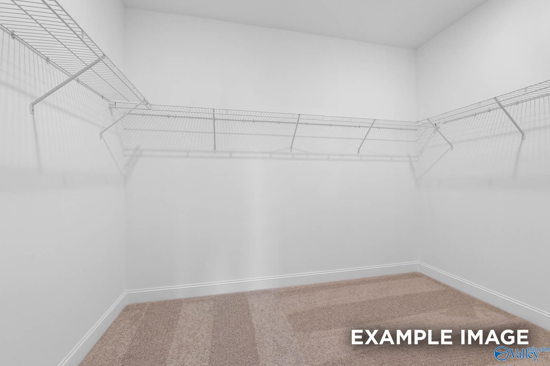 Spacious walk-in closet with wire shelving and carpeted floor in The Oxford master suite, Davidson Homes, Huntsville, Alabama
