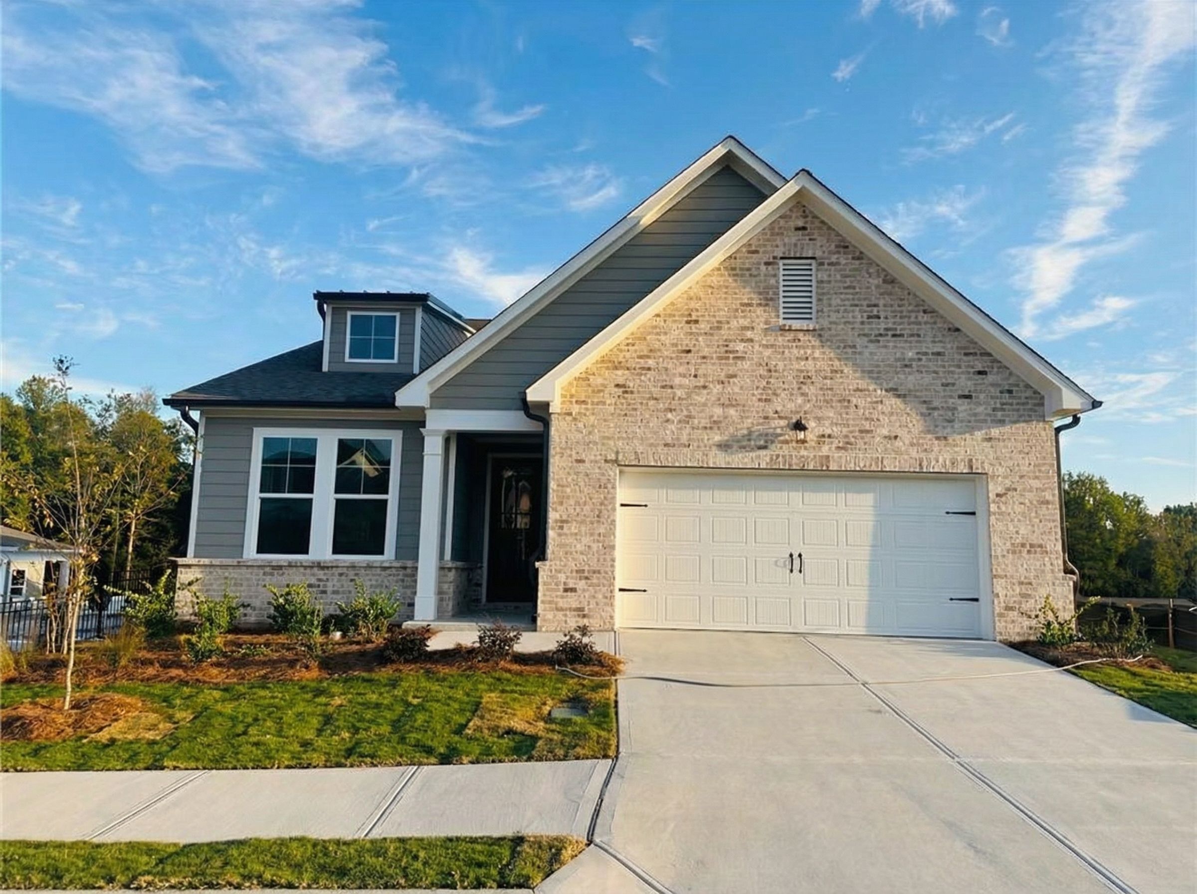 Modern gray brick ranch home with 2-car garage, gabled roof, and front yard landscaping in Davidson Homes The Glenwood C, Kelly Preserve, Loganville, GA