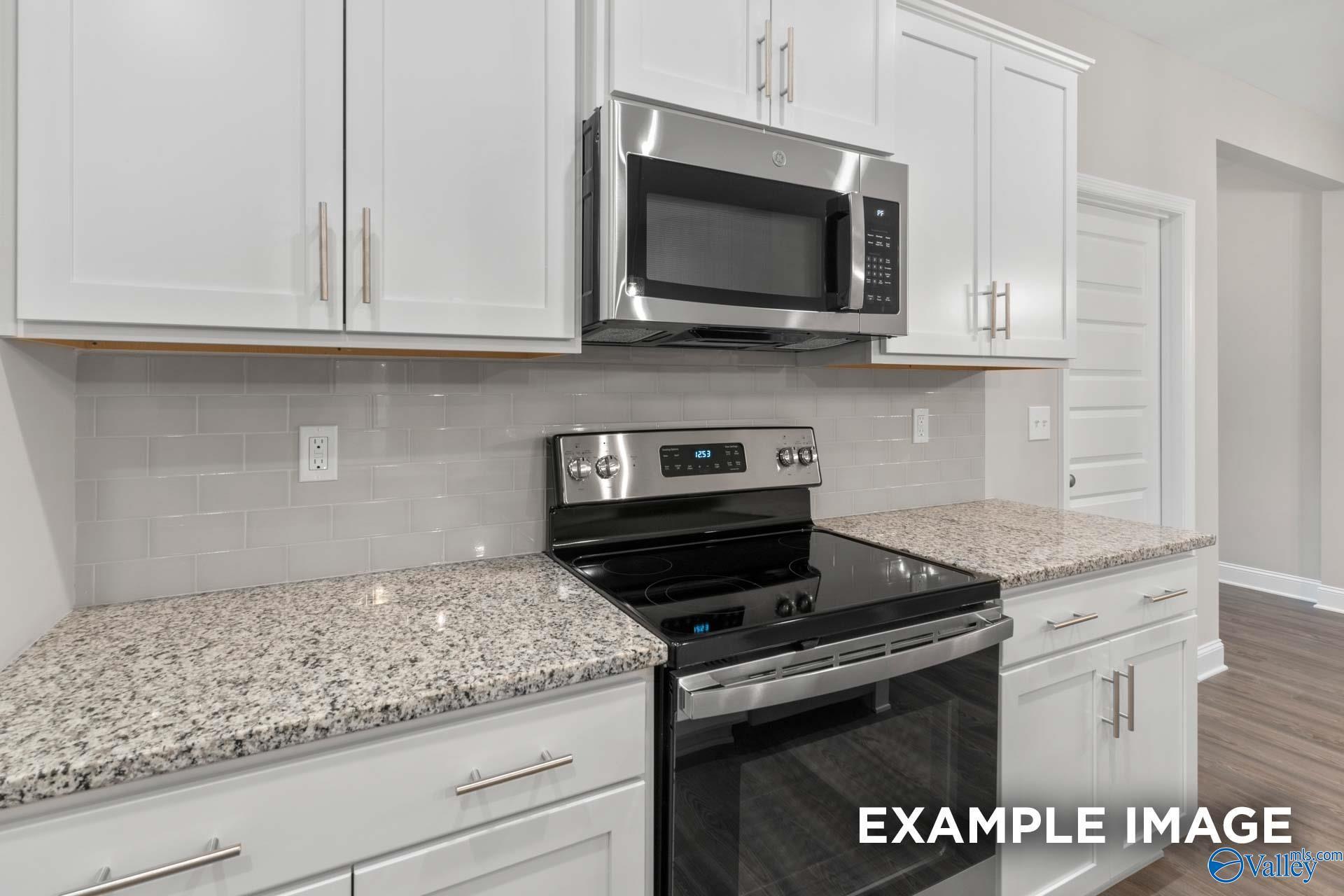 Modern kitchen with granite countertops, white cabinetry, and stainless appliances in The Camilla C home at Cain Park.