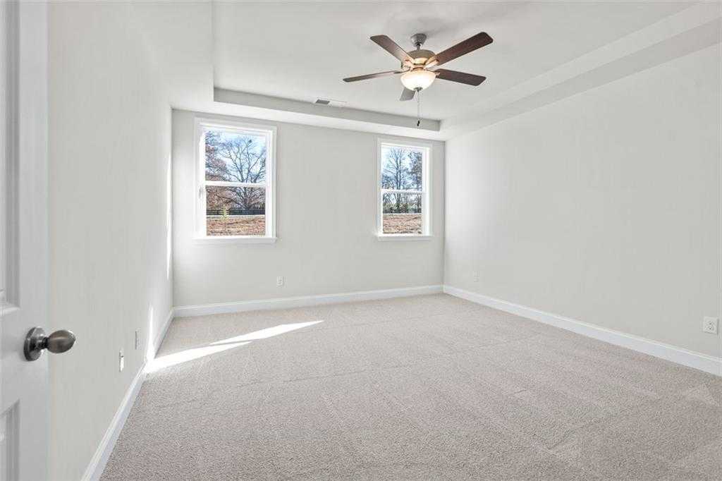 Bright bedroom with ceiling fan, large windows, and plush carpet in Davidson Homes The Ash C at Wehunt Meadows, Hoschton